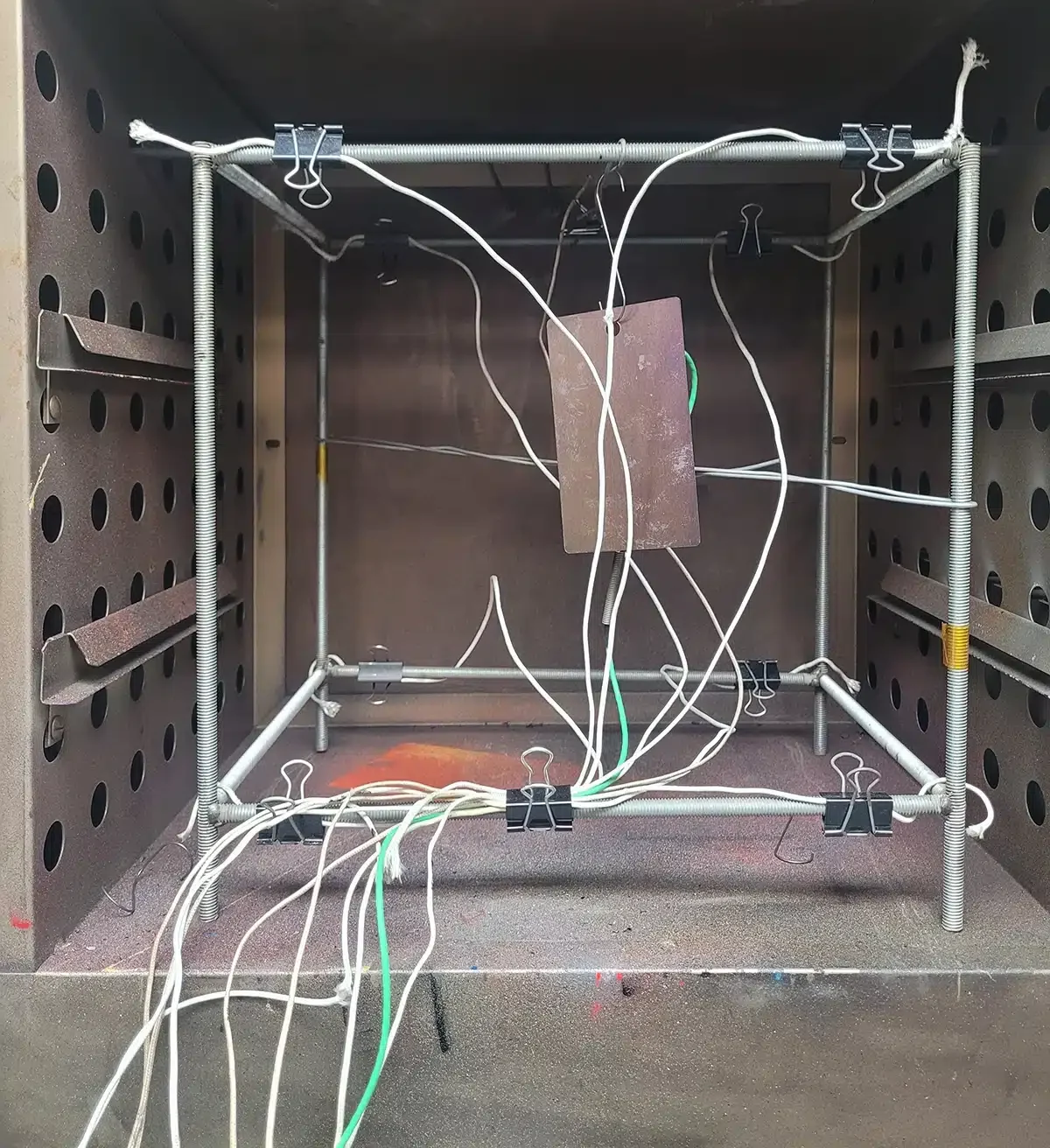 A standard 9-point thermocouple sensor fixture setup inside a laboratory benchtop oven for precise chamber uniformity testing.